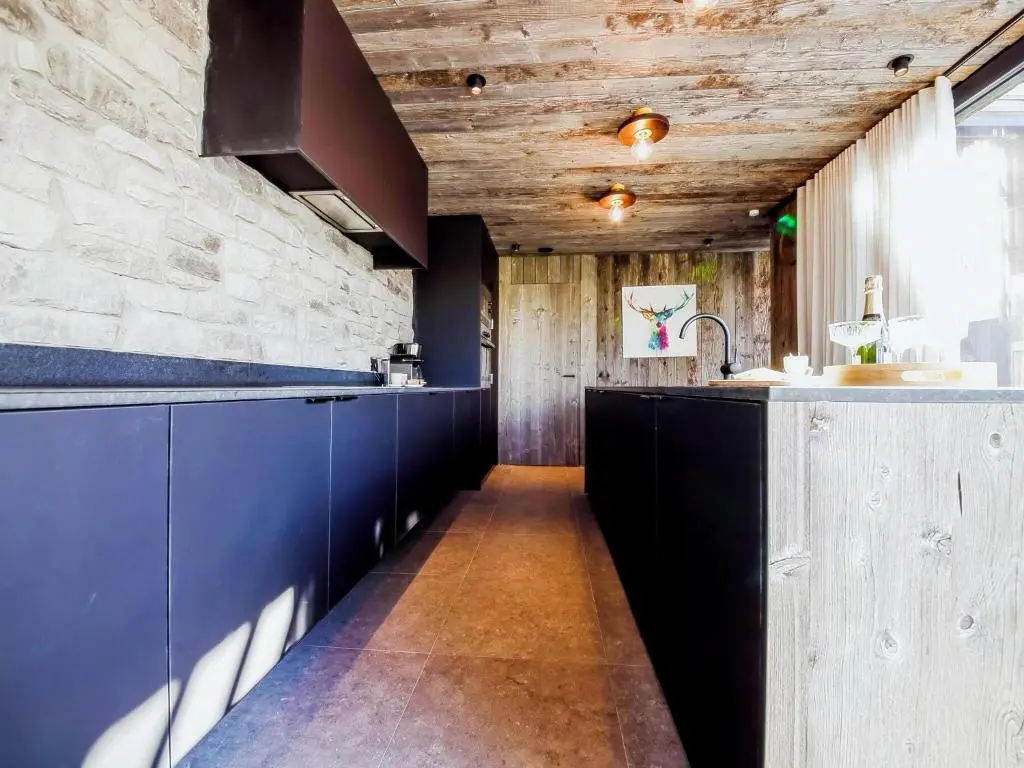 Interior with reclaimed wood wall cladding and rustic timber finishes combined with a modern kitchen design