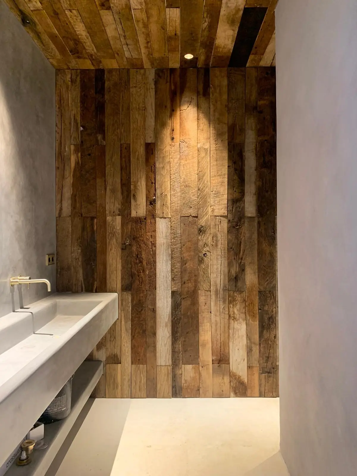 Interior wall finished with reclaimed wood paneling in mixed weathered wood shades and vintage character
