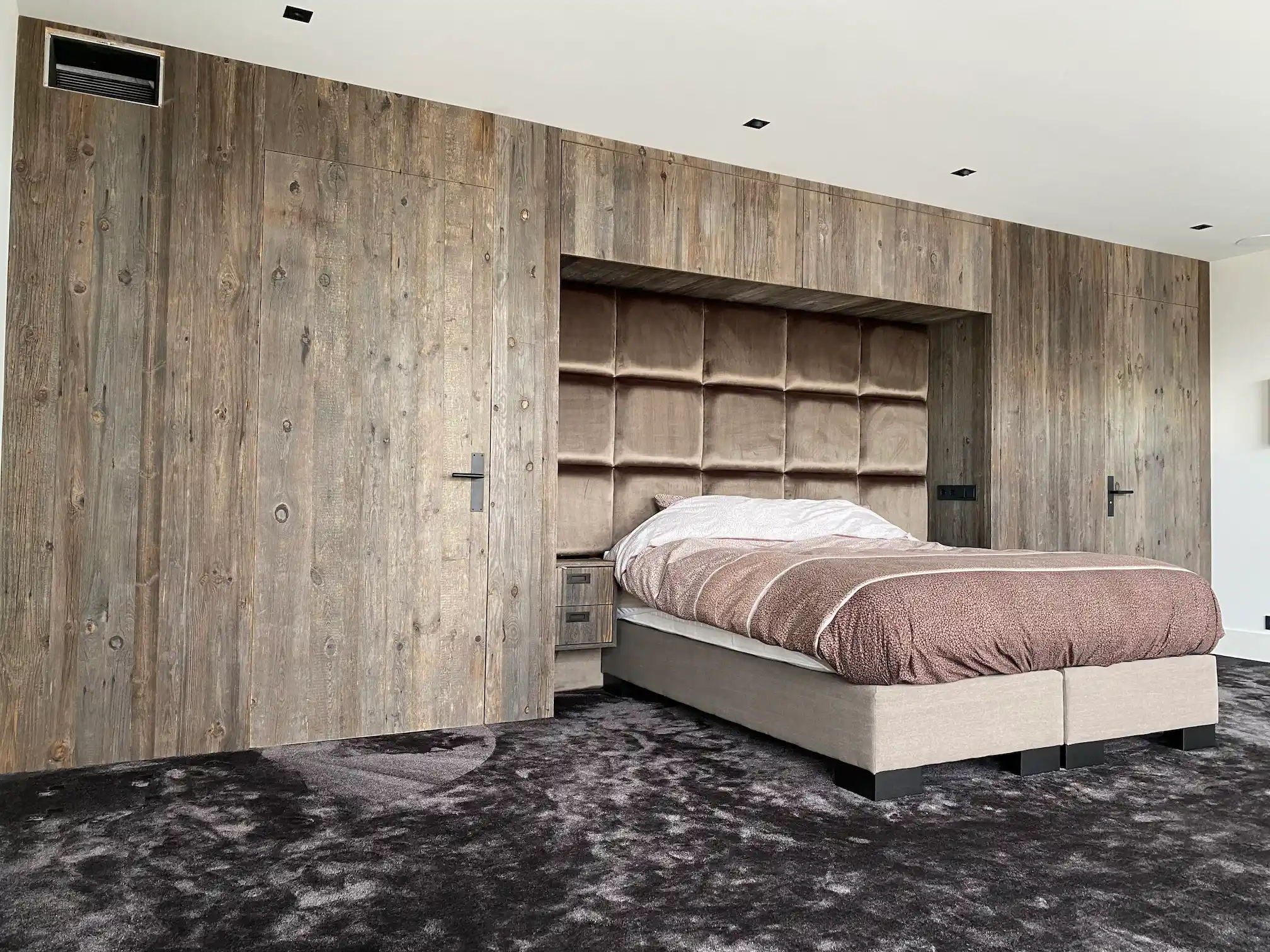 Reclaimed plywood wall panels creating a calm and natural atmosphere in a luxury bedroom