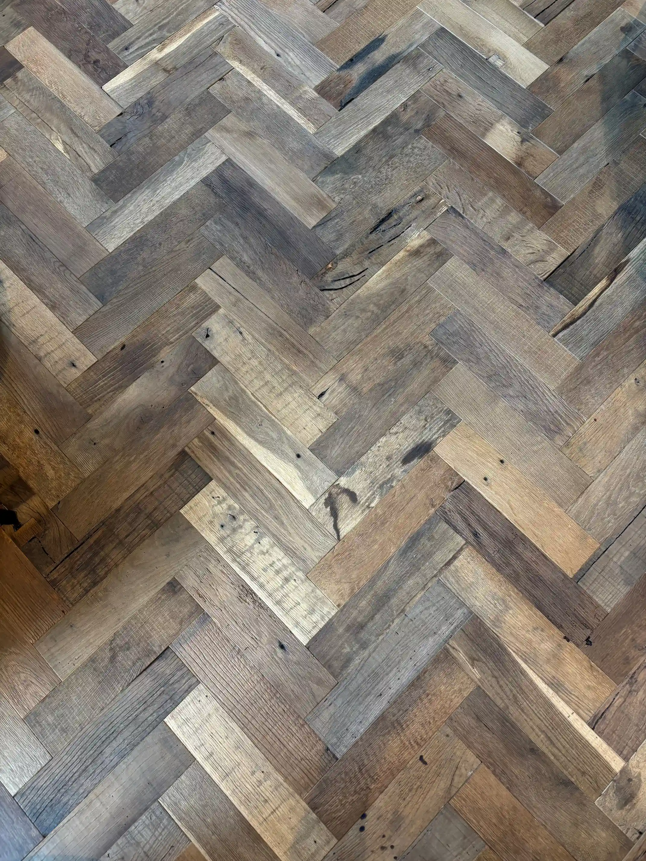 Reclaimed oak herringbone floorboards with natural imperfections and timeless wooden appearance