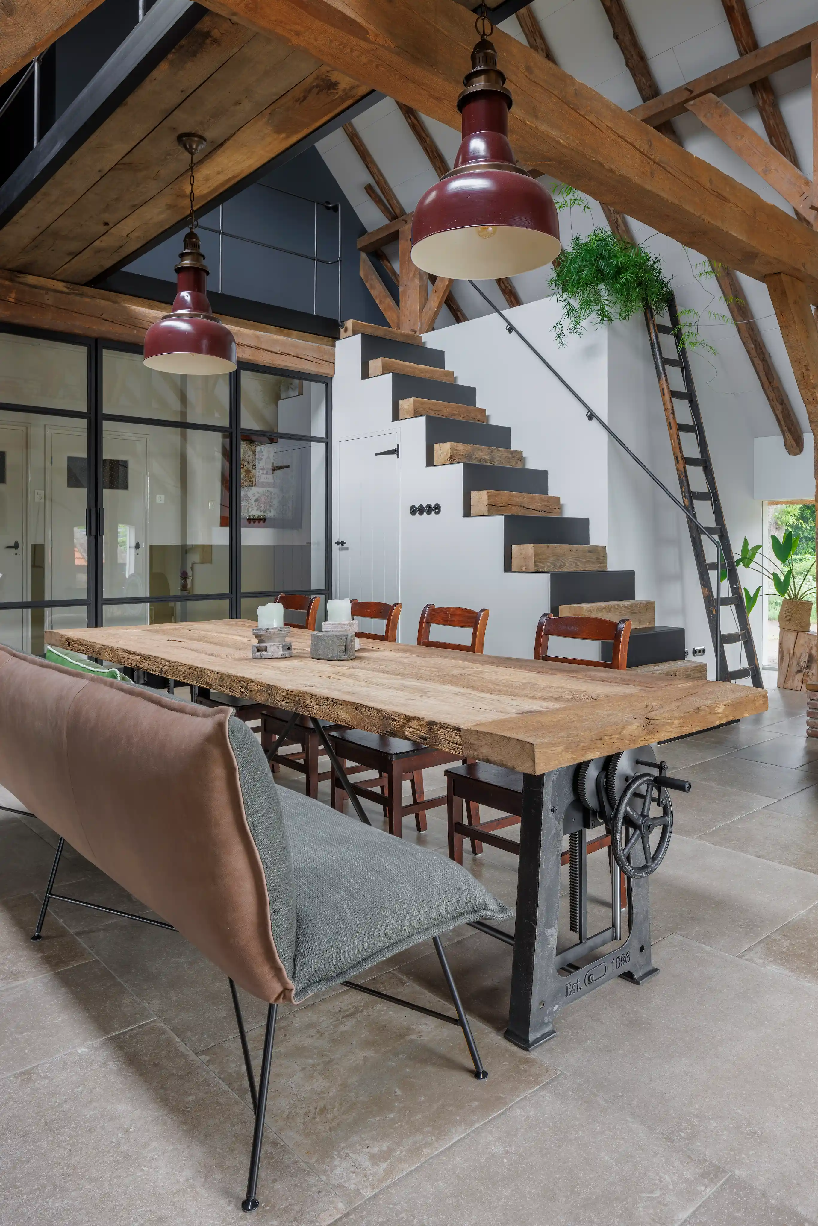 Rustic oak dining table with industrial steel base in a modern loft interior.