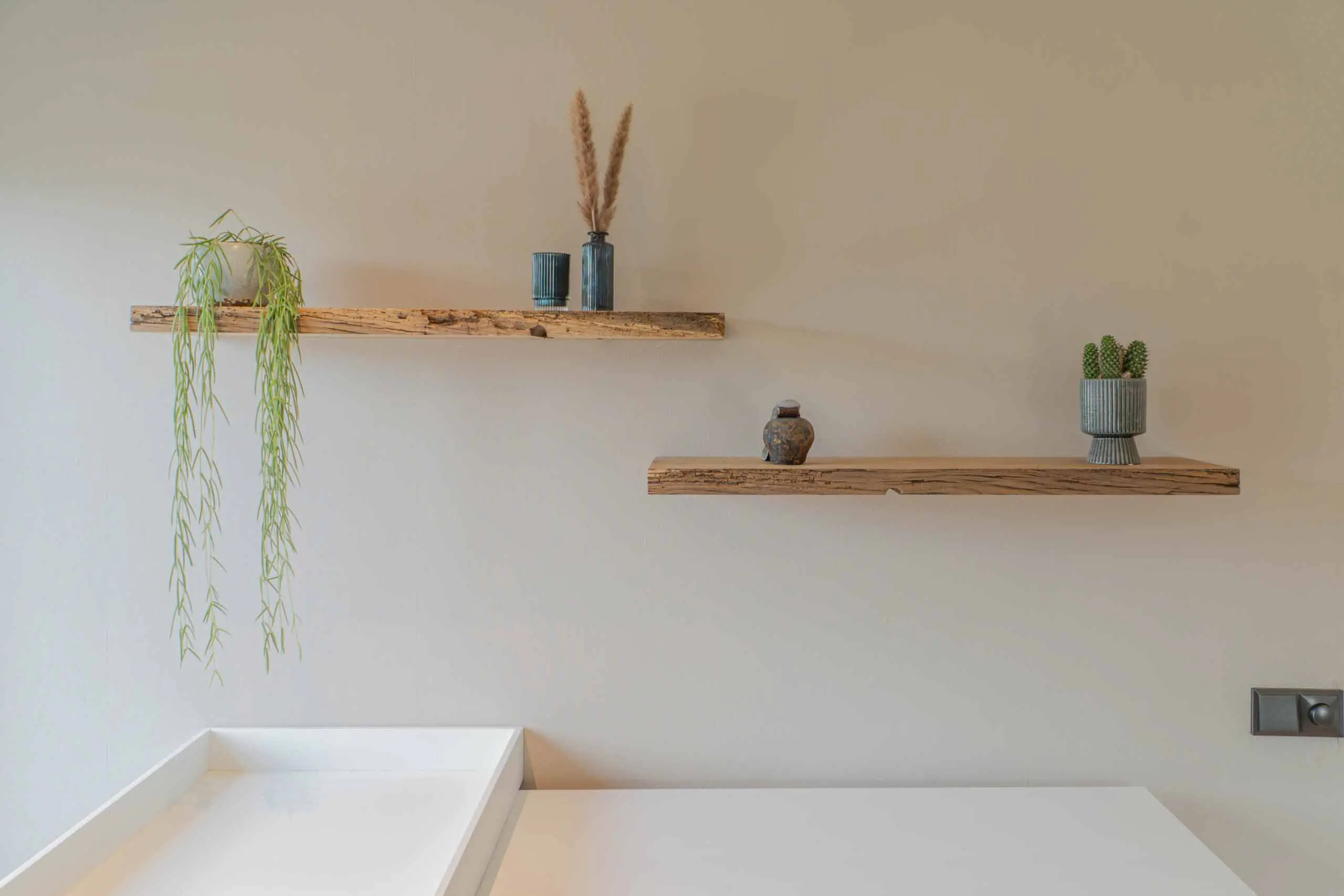 Minimalist reclaimed wood floating shelves mounted on a light wall in a modern interior