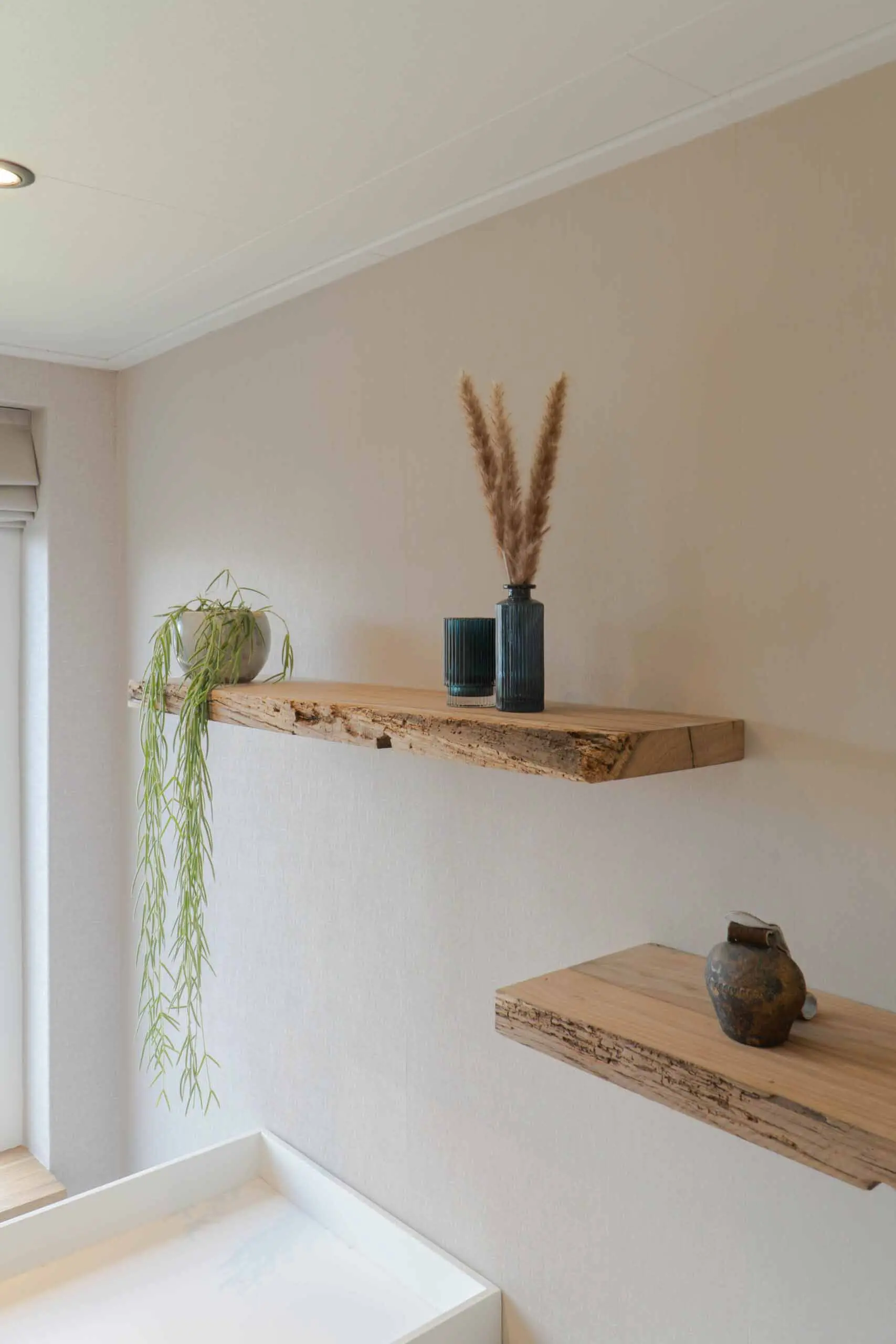 Rustic reclaimed wood shelf mounted on a light wall with authentic aged timber texture