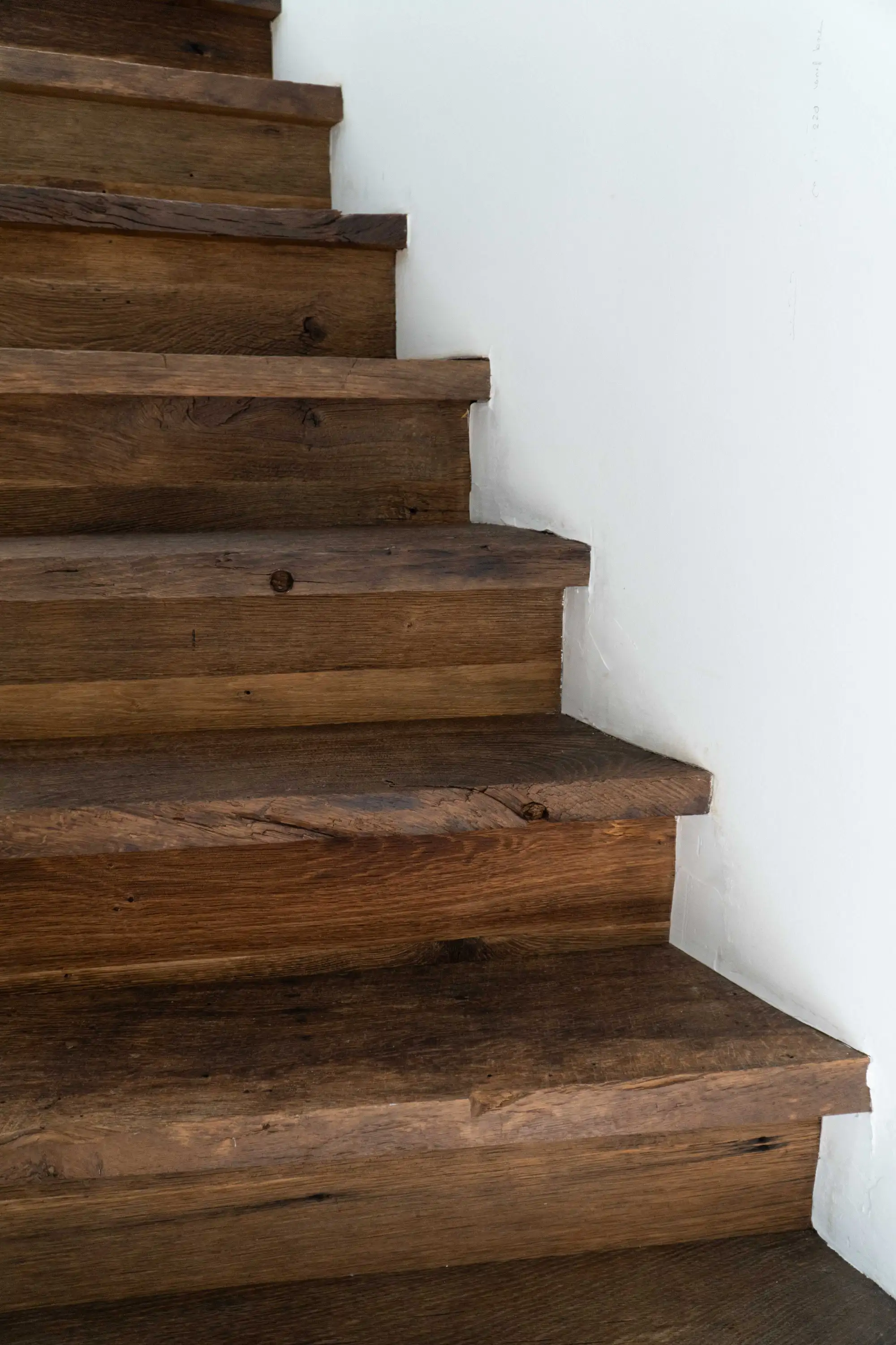Reclaimed oak staircase with rich natural textures and warm wood tones, creating a striking contrast within a contemporary home interior