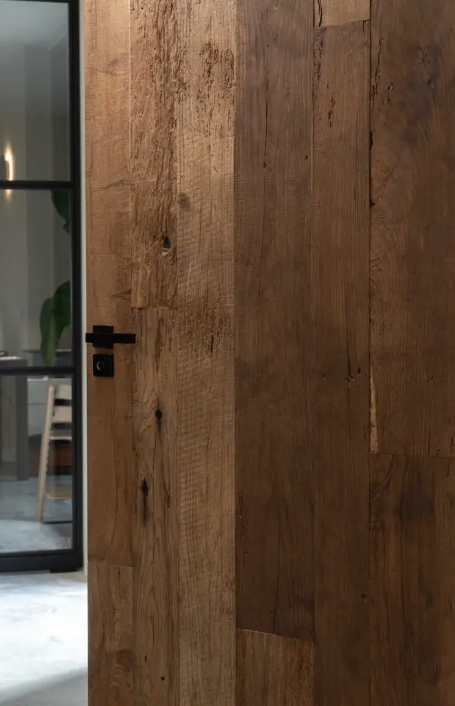 Reclaimed oak door with authentic wood grain and natural textures, creating a warm and characterful transition between living spaces in a modern home