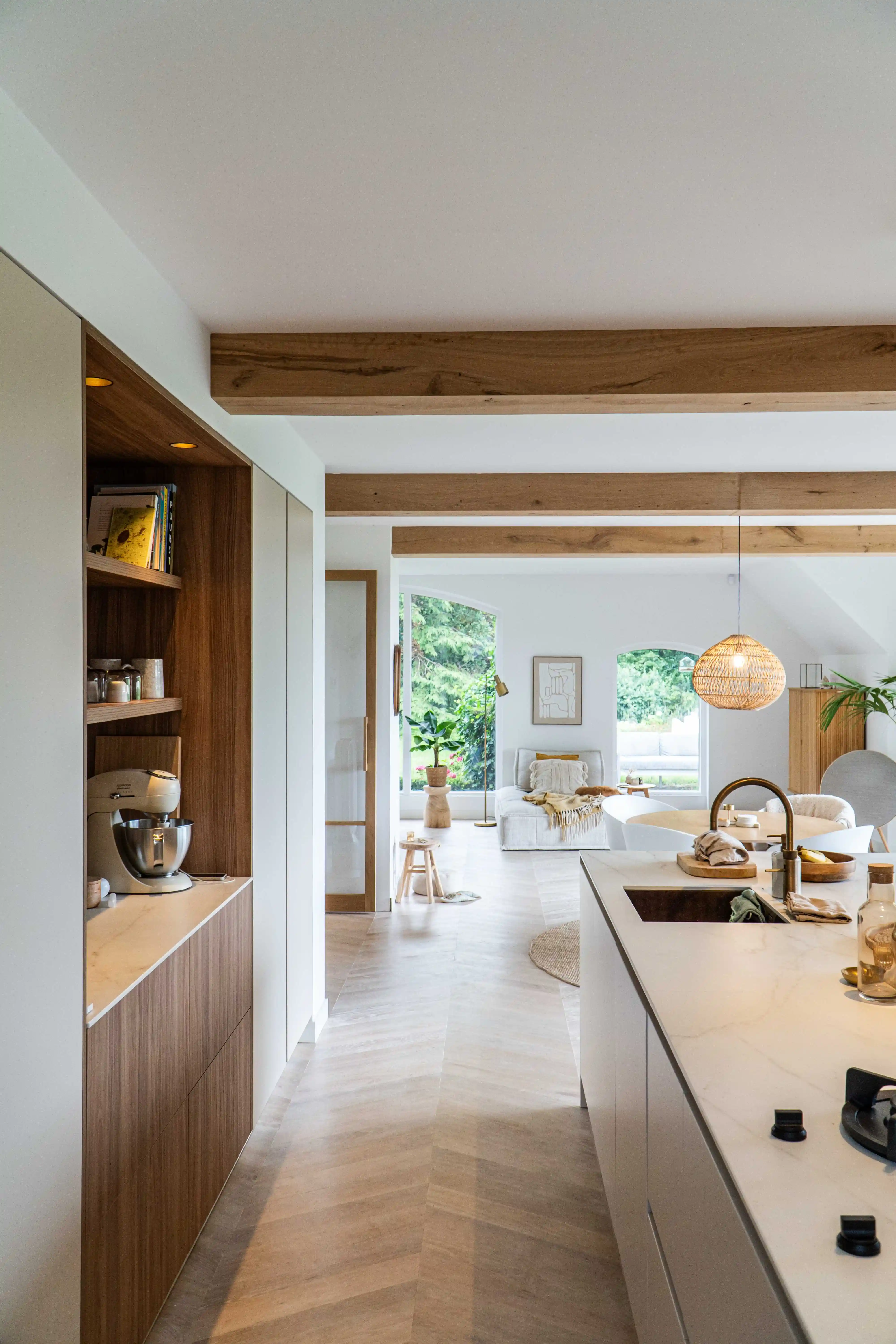 View from the kitchen into a bright farmhouse living space in Deventer, featuring antique oak beam cladding.