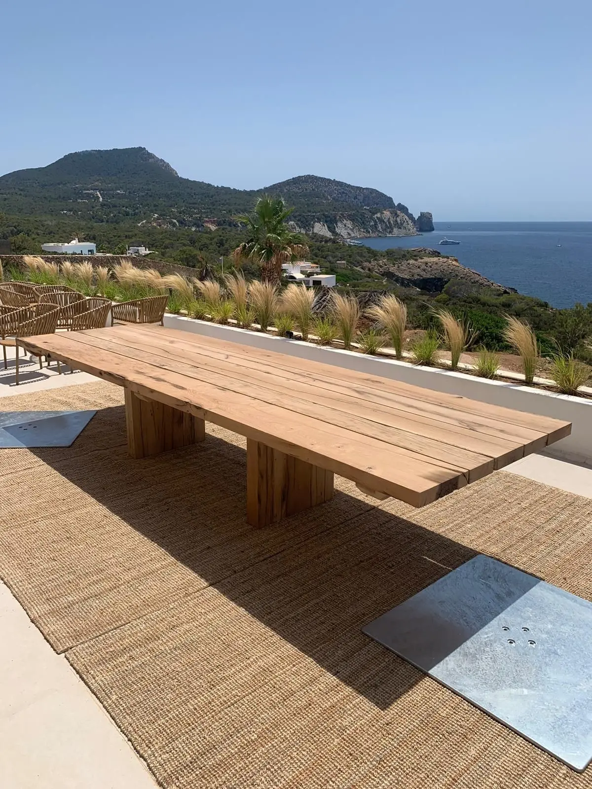 Large reclaimed oak outdoor dining table on a sunny terrace with sea and mountain views