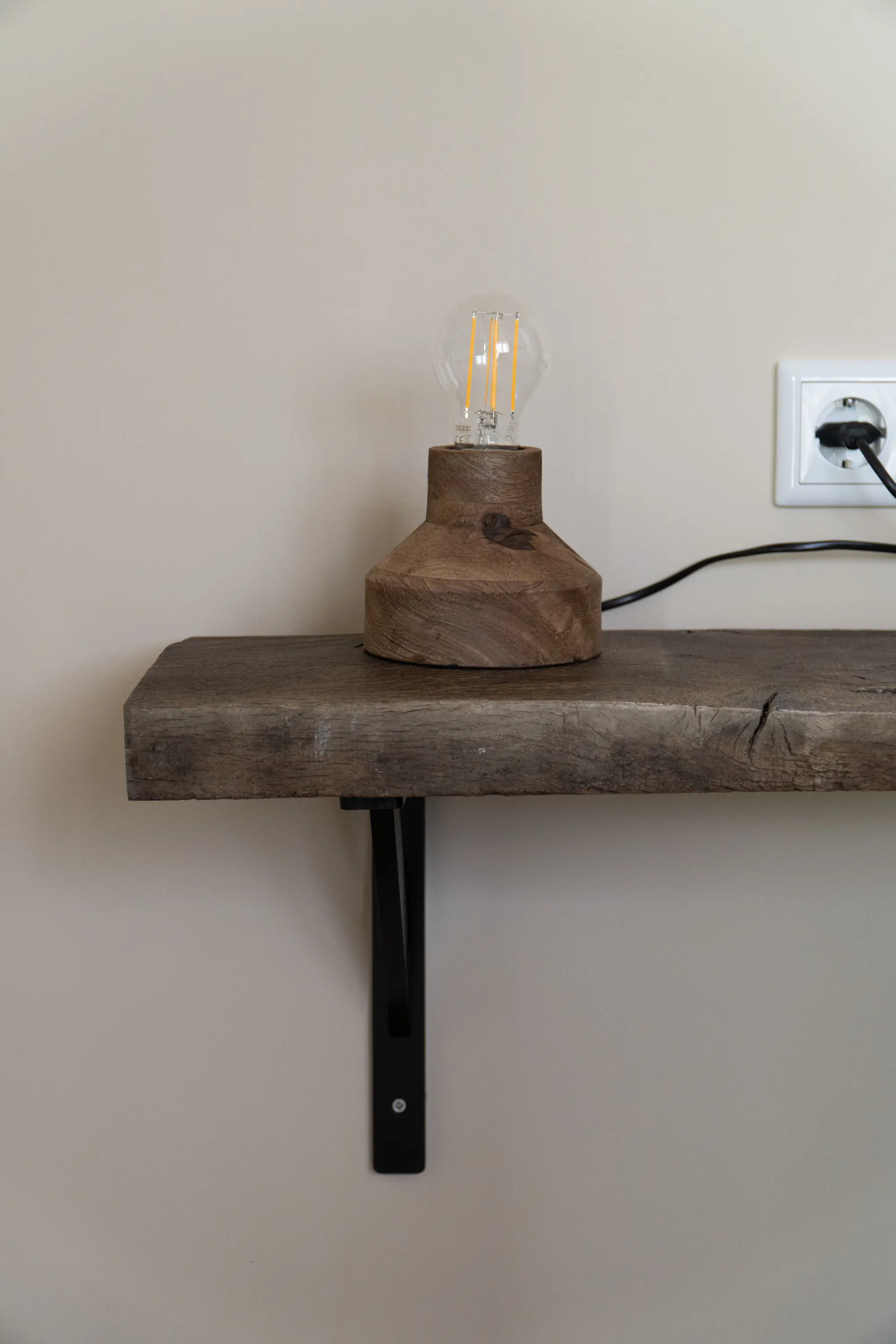 Rustic reclaimed oak wall shelf with a black metal bracket, showcasing the natural character of old oak from Historisch Hout.