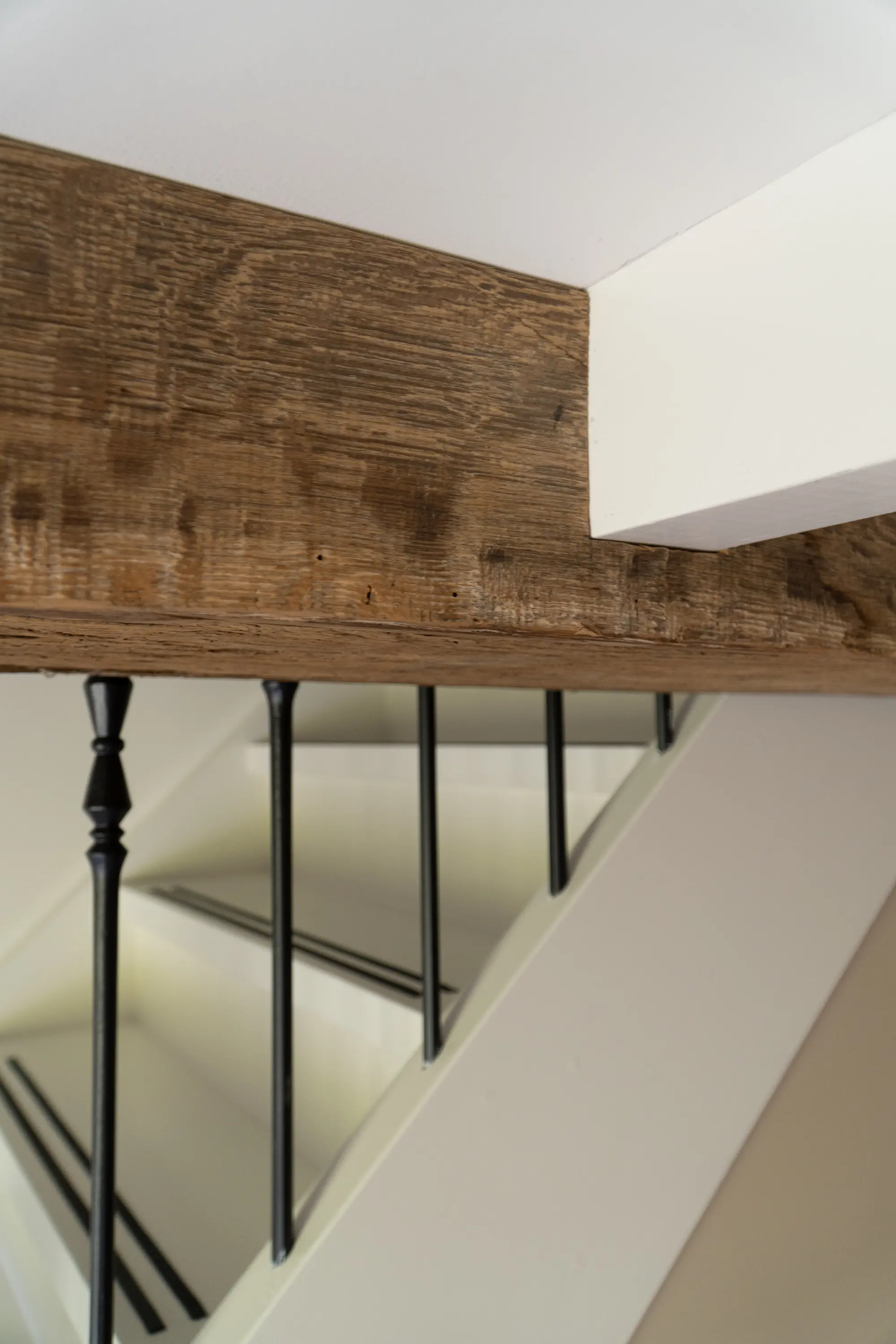 Characterful reclaimed oak wall cladding beside a staircase, combined with black metal railings