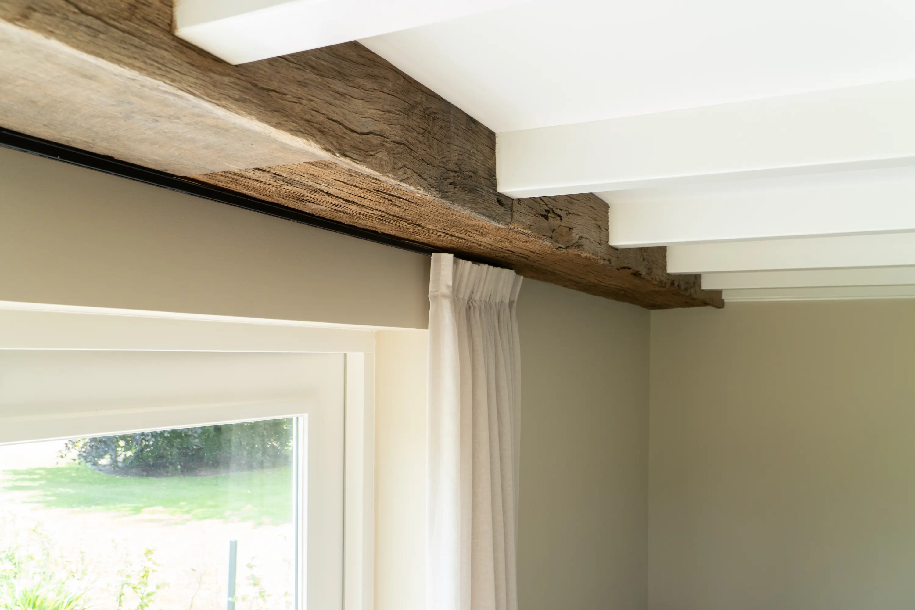 Authentic reclaimed oak beam fitted along a white ceiling, adding a warm and rustic detail to the interior