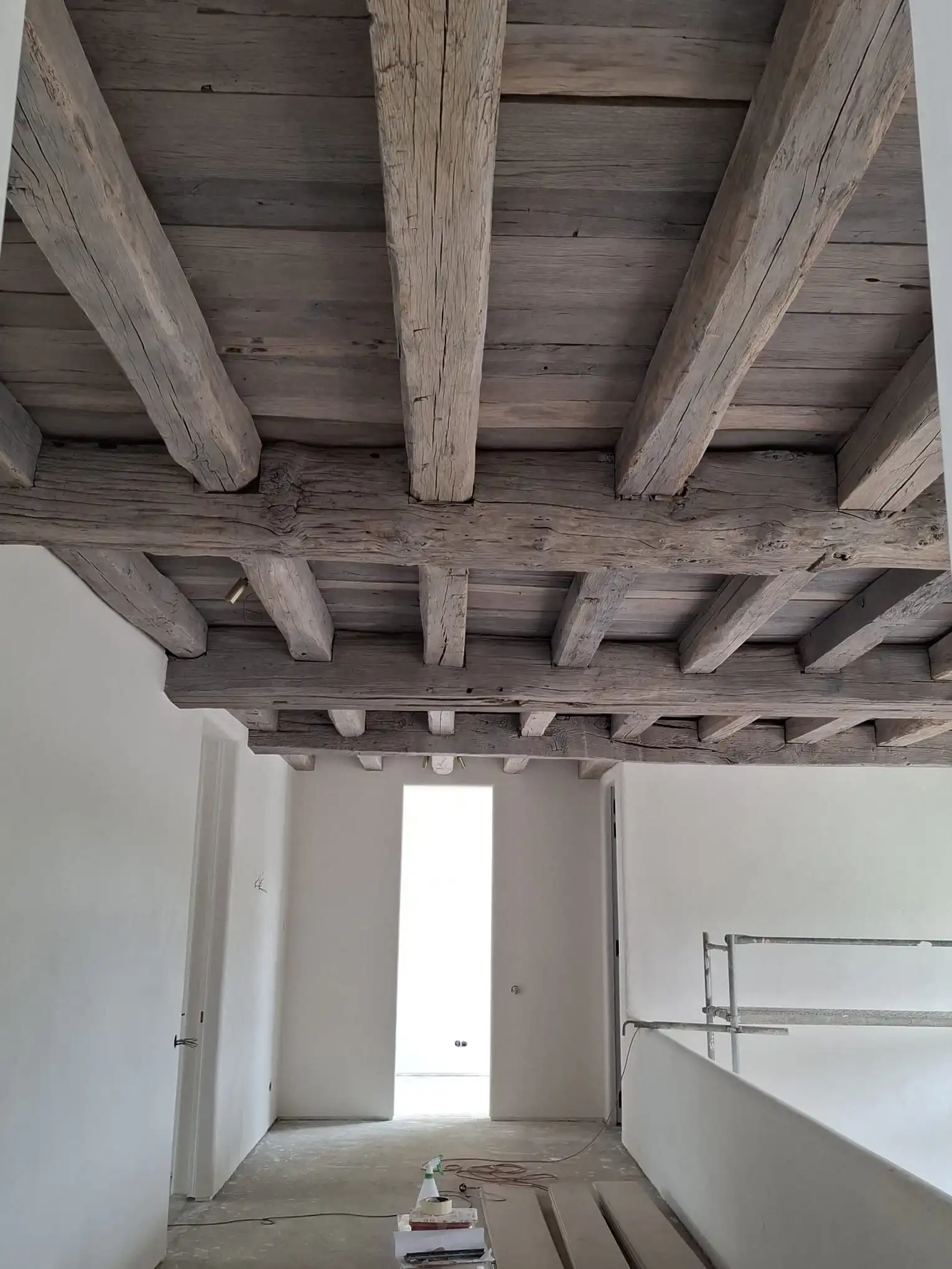 Reclaimed oak beams used as ceiling cladding in a bright interior