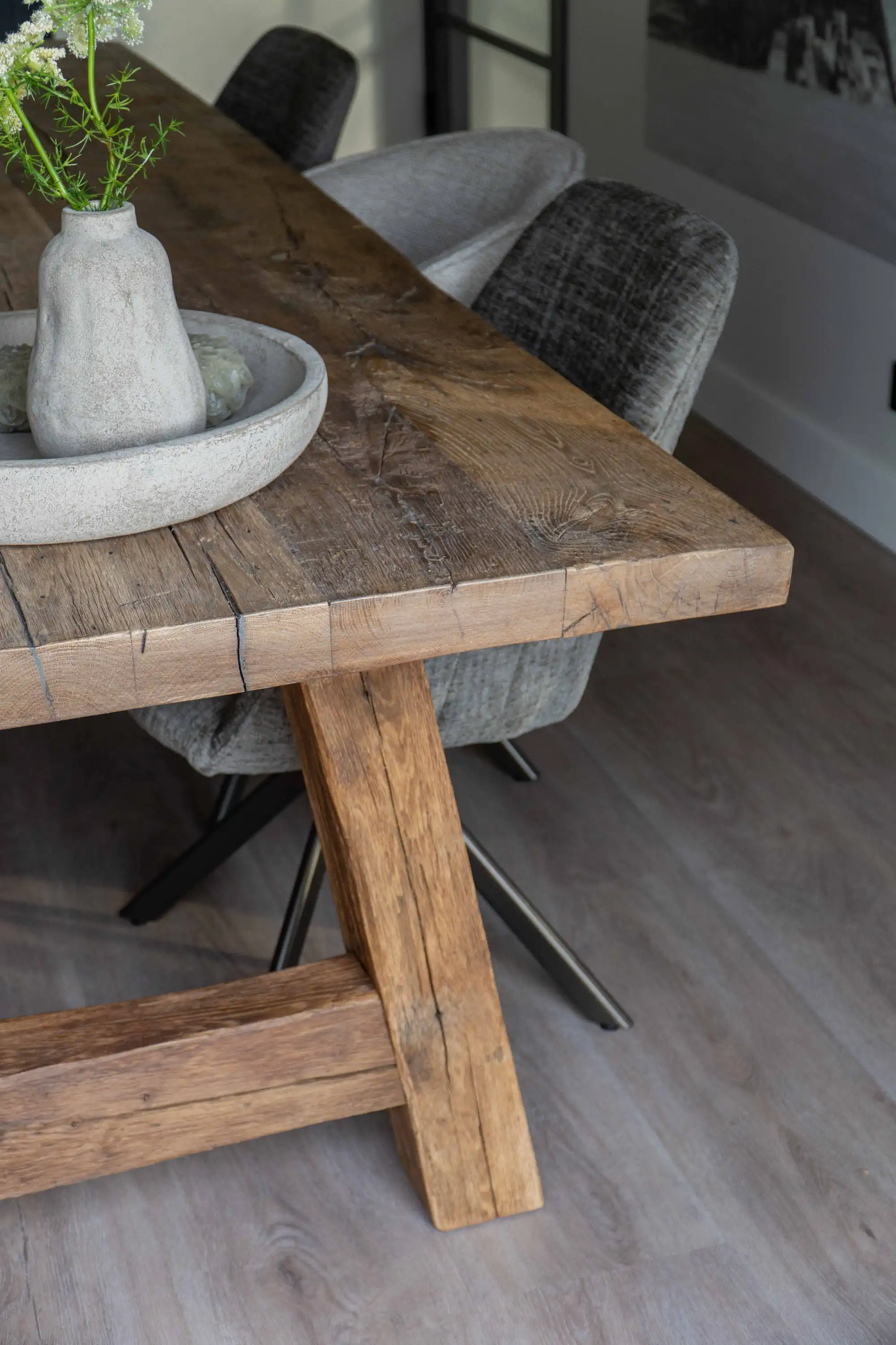 Rustic reclaimed oak dining table with a sturdy trestle base and naturally weathered tabletop in a modern dining area.