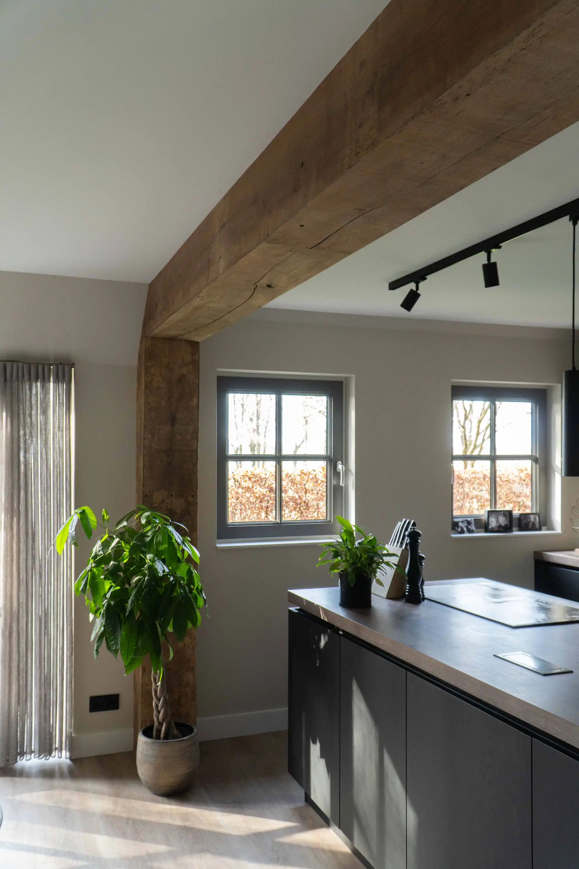 Reclaimed oak beam cladding in a modern kitchen interior with dark cabinetry and natural wood details.