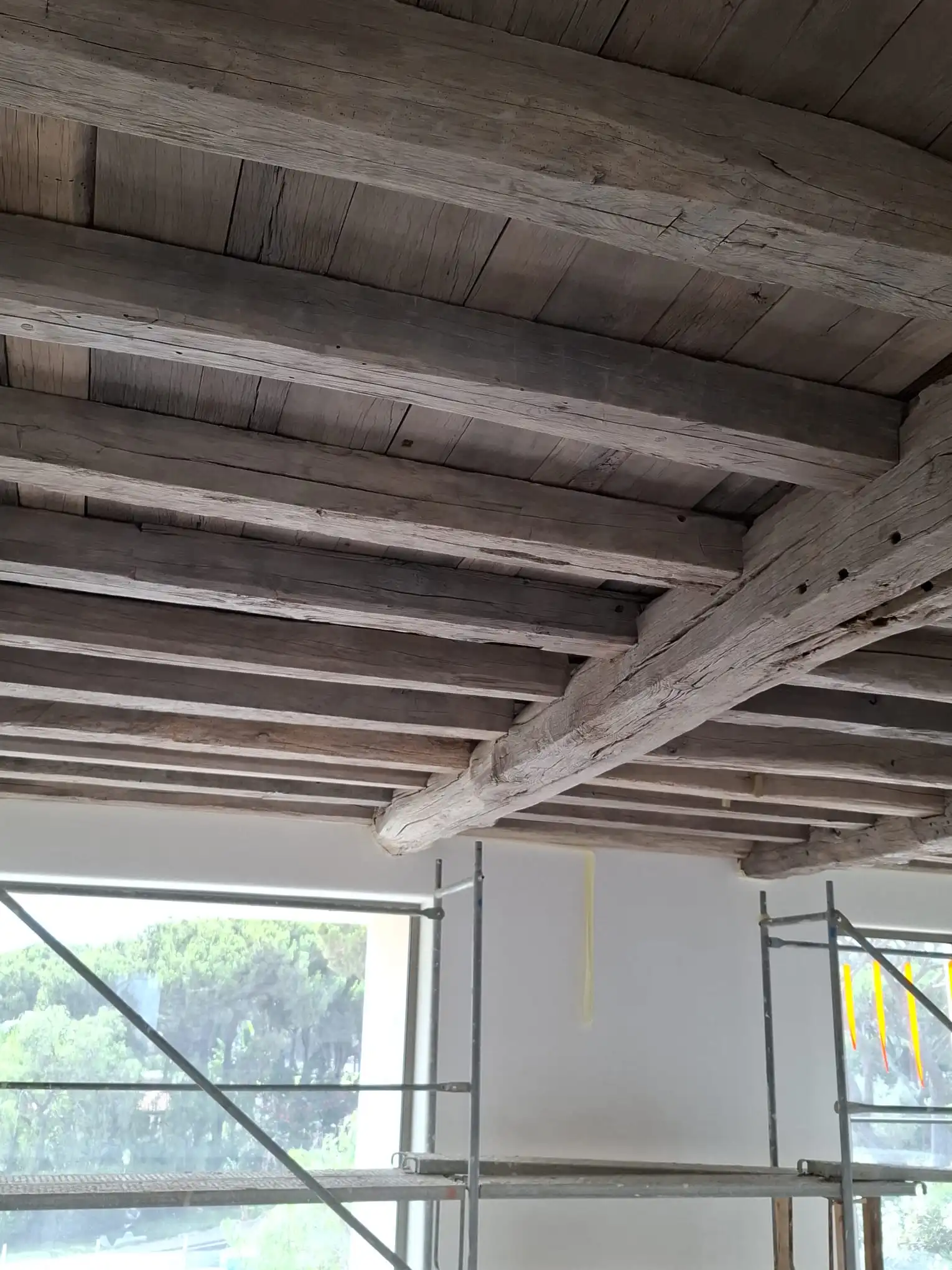 Authentic reclaimed oak beams installed across a ceiling, adding a warm and rustic character to the interior