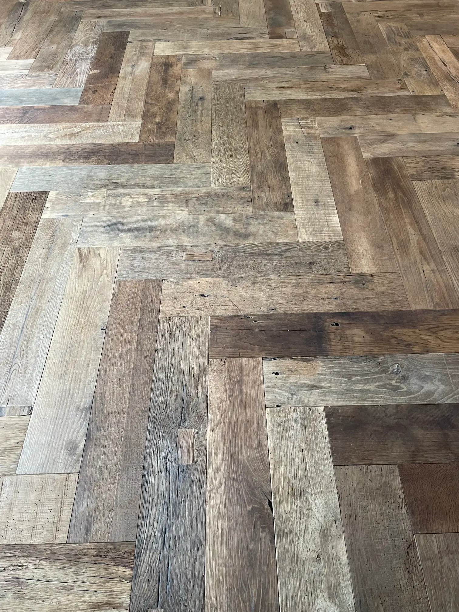 Close-up of reclaimed oak herringbone flooring with natural colour variations and authentic wood character