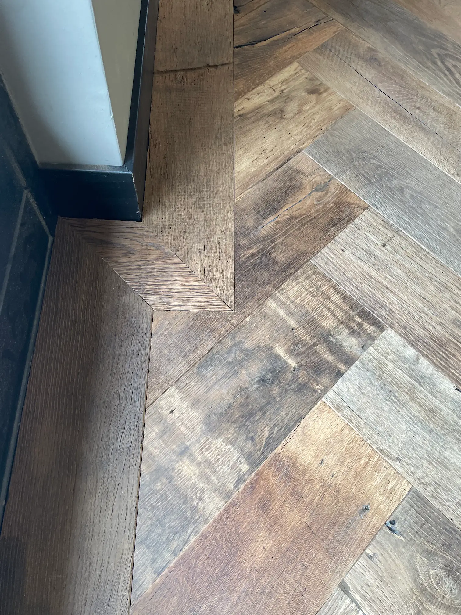 Detail of a reclaimed oak herringbone floor with natural colour variations and characteristic wood grain