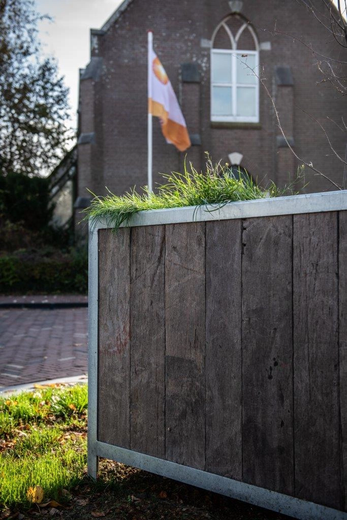 Tall outdoor planter made from reclaimed Azobé ship planks in a landscaped park setting